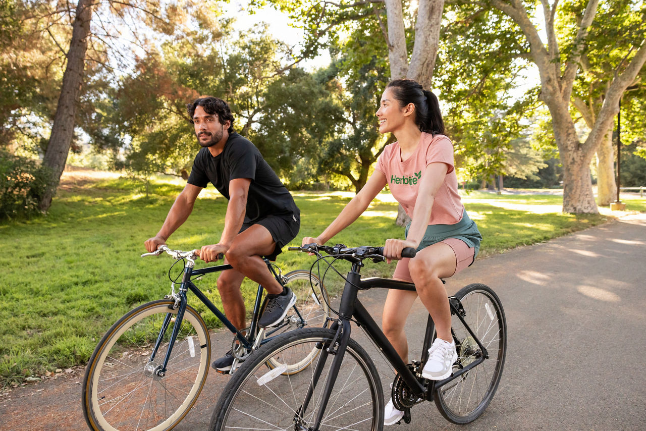 Man and woman riding their bicycles in a park.
