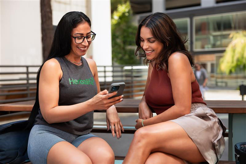 Two women smiling while looking at a cell phone