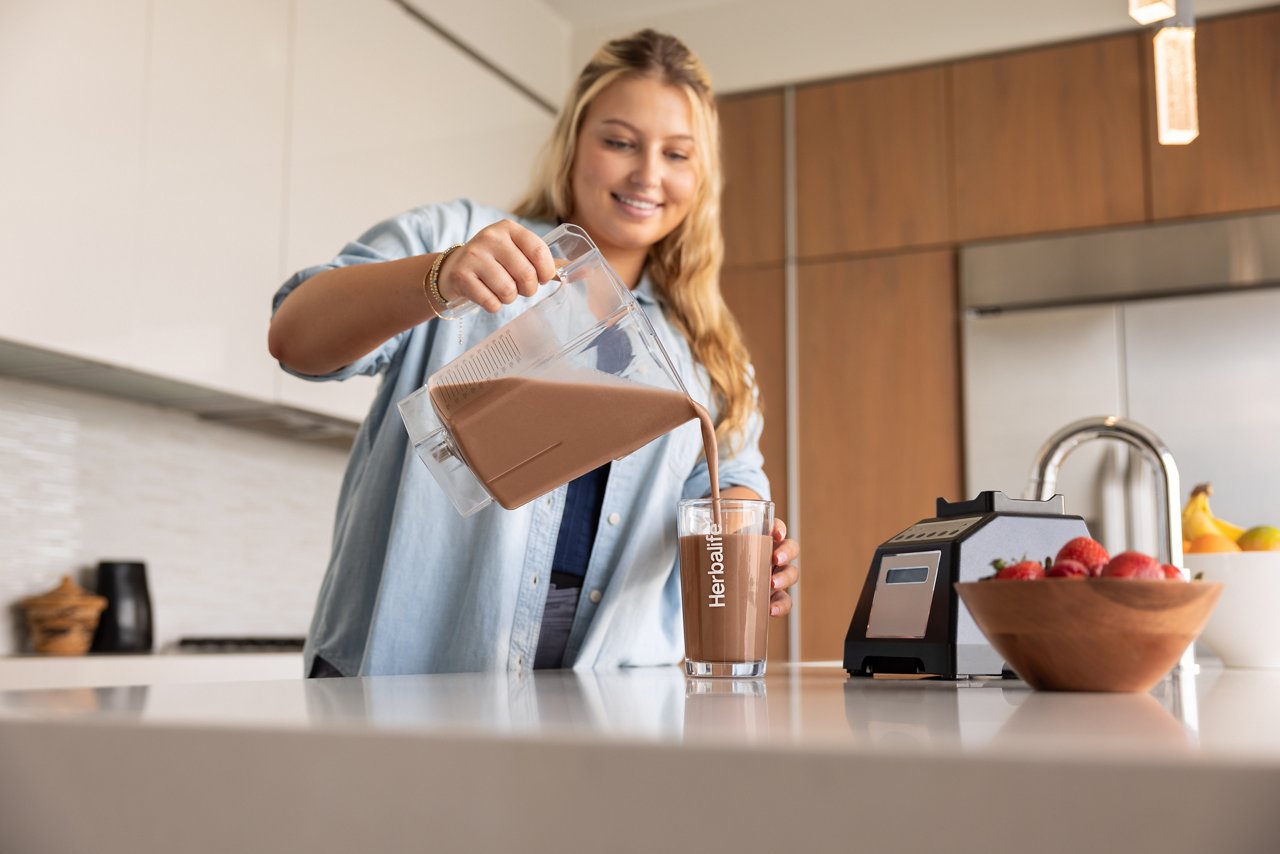 Woman smiles before enjoying an Herbalife Formula 1 meal replacement shake in her home.