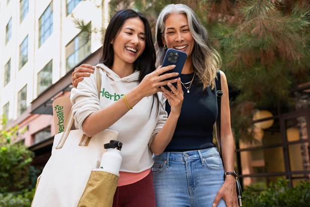 Two women laughing and looking at a phone.